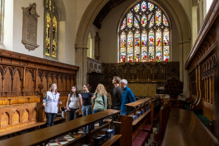 Group of people touring a historic church interior with stained glass windows.