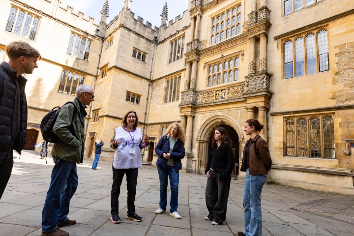 Group of people on a tour outside historic building with ornate architecture.
