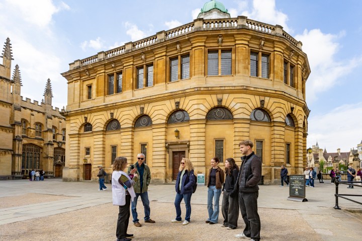 Group of people in front of a historic building with a dome on a sunny day.