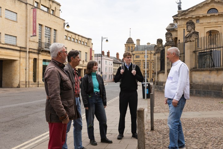 Group of five people talking on a city street near historic buildings.