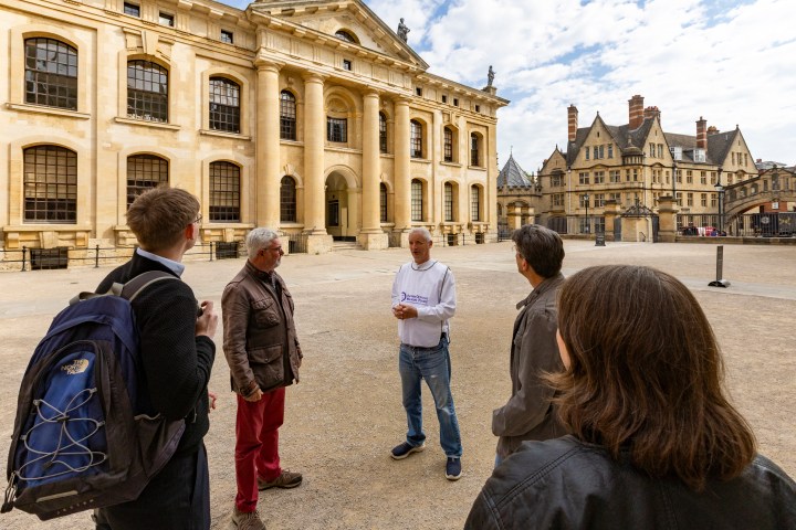 Group of people talking in front of a historic building on a sunny day.