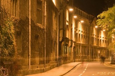 Dimly lit street with old stone buildings and streetlights at night.