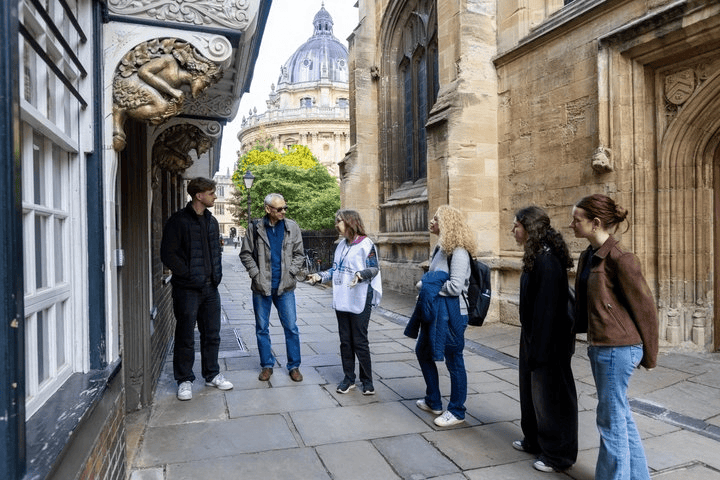 Tour group with guide near historic buildings in a cobblestone alley.