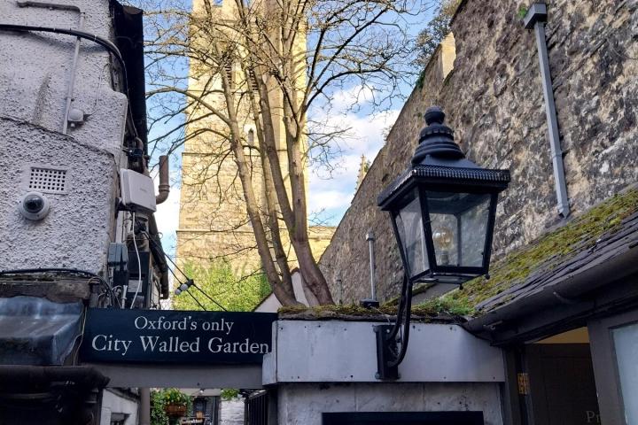 Narrow alley with 'Turf Tavern' sign, tree, and stone wall in Oxford.