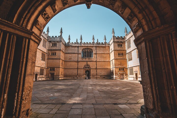 Historic building courtyard viewed through an arched entrance with ornate windows and stone walls.