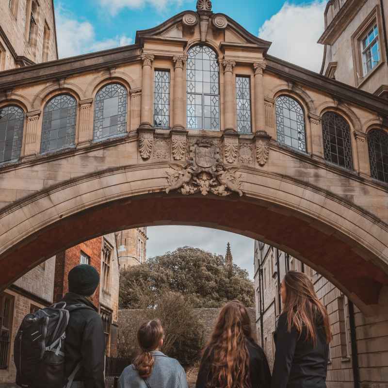 a group of people standing in front of a brick building with Bridge of Sighs in the background