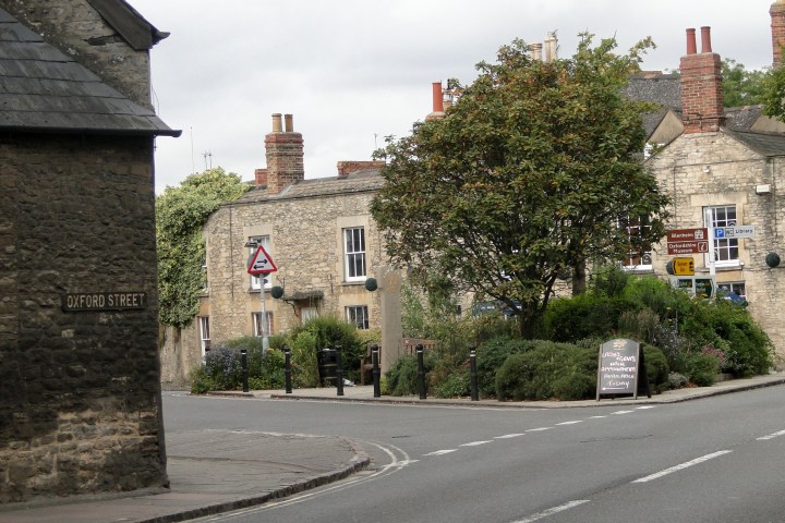 Stone buildings and street signs at Oxford Street intersection with greenery.