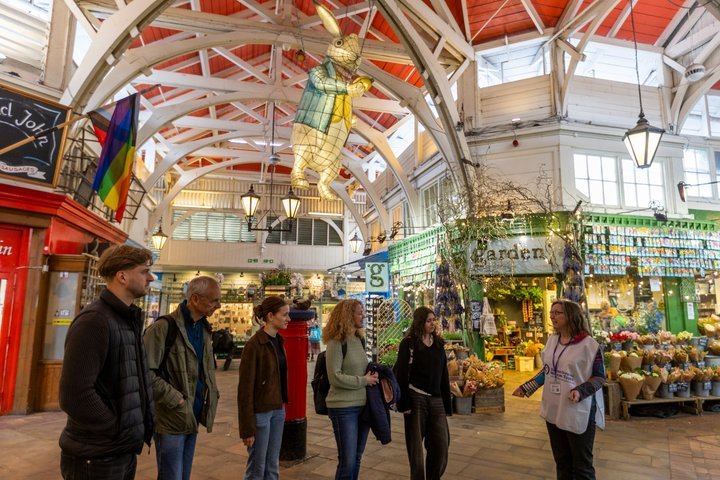 Group of people touring a vibrant indoor market with colorful shops.