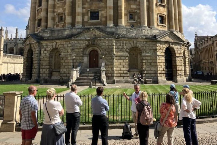 People stand outside a historic round building with a dome under a clear sky.
