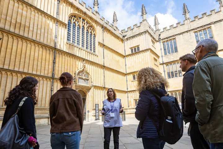 Group of people on a guided tour outside an ornate historical building.