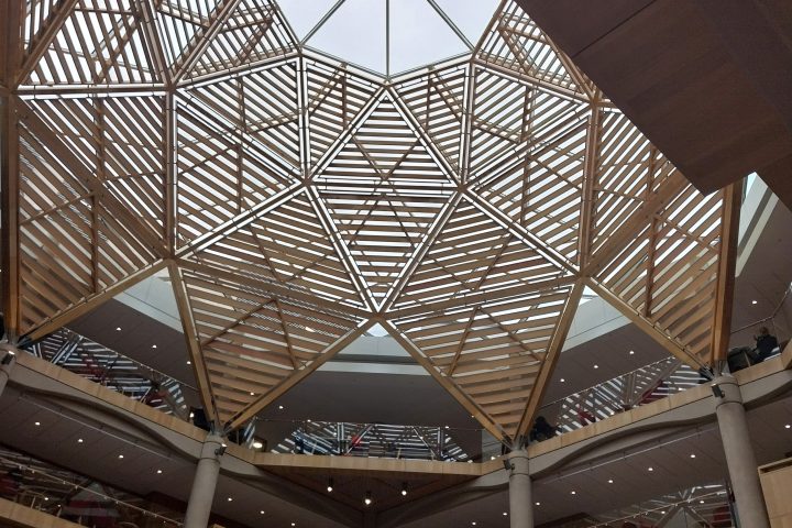 Geometric wooden skylight in a building interior with multiple floors.