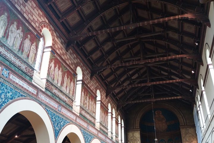 Interior of a church with a wooden ceiling and arched windows.
