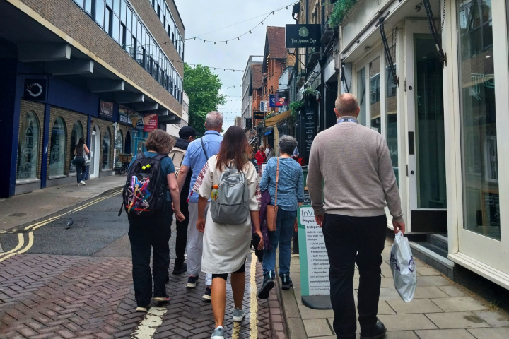 People walking on a narrow street with shops and brick buildings.