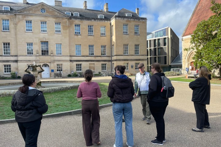 Group of people standing outside a historic building on a sunny day.