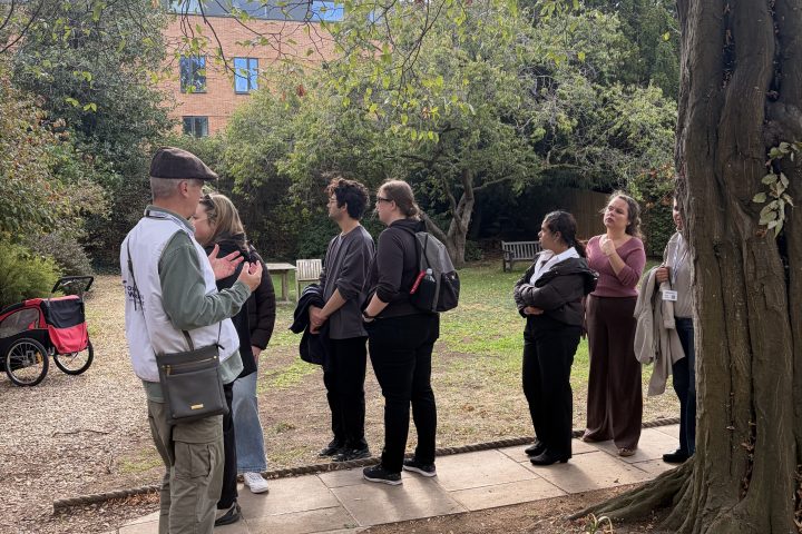 People gathered on a path beside a tree and lawn.