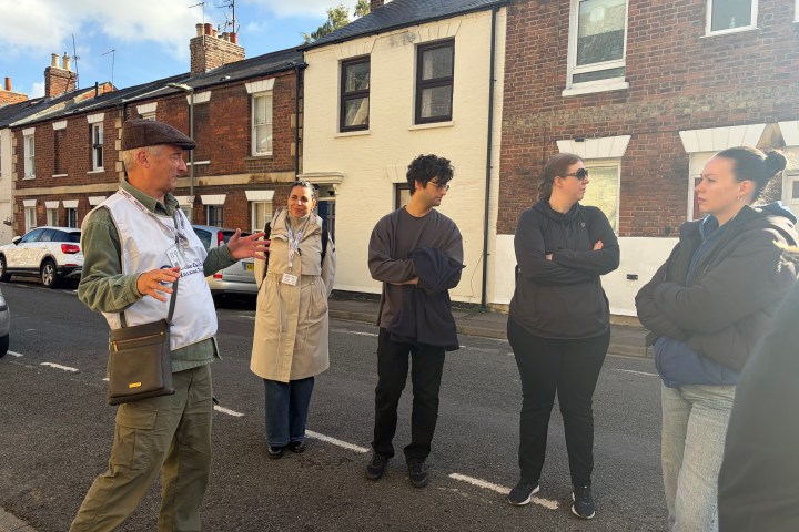 Group of people talking on a residential street with brick houses.