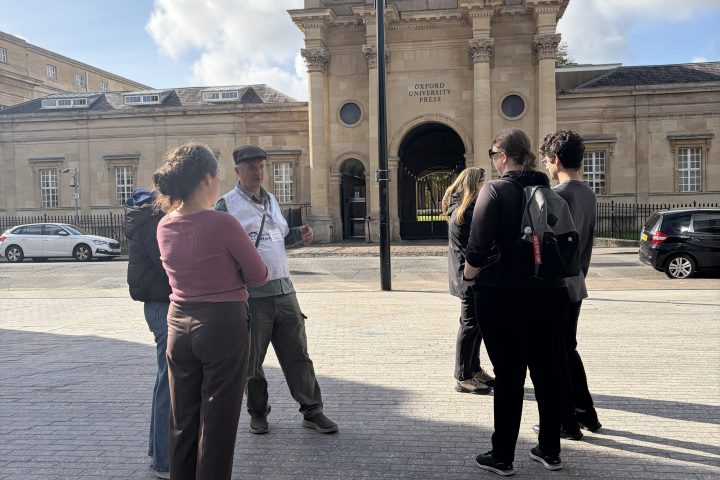 Group of people talking outside a historic building on a sunny day.