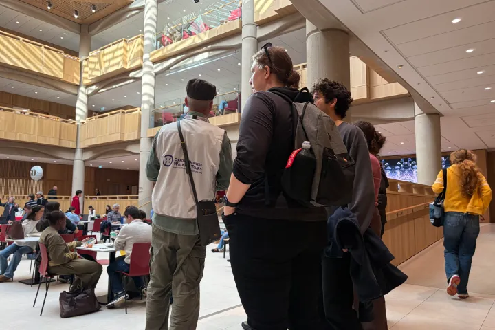 People gathering in a spacious atrium with tables and balconies visible.